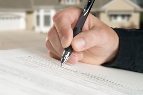 hand holding pen signing paperwork