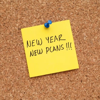 yellow post it note that says New Year New Plans pinned to bulletin board