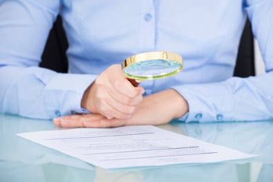 person reading a paper with a magnifying glass