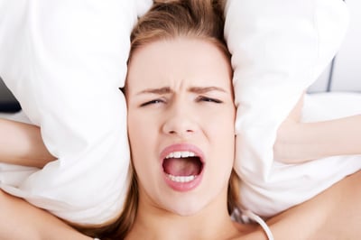 woman covering ears with pillow