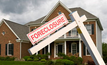 foreclosure sign posted in front of brick house