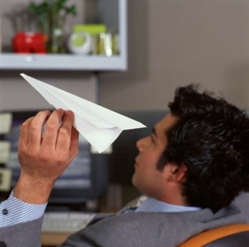 man at desk with paper airplane