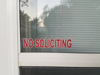 red no soliciting sign on white door