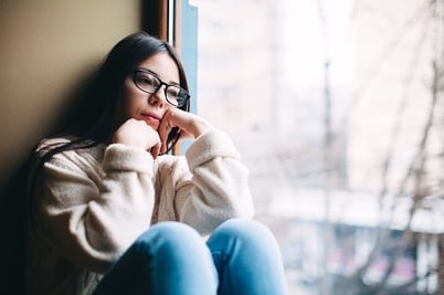 sad girl sitting by window in winter