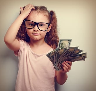 young_girl_in_glasses_scratching_head_holding_handfull_of_money