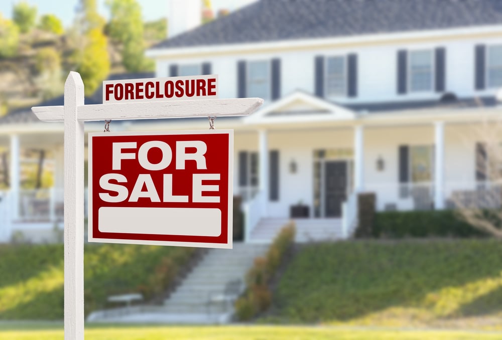 foreclosure sign in front of large white house